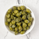 Bowl of capers on white marble countertop